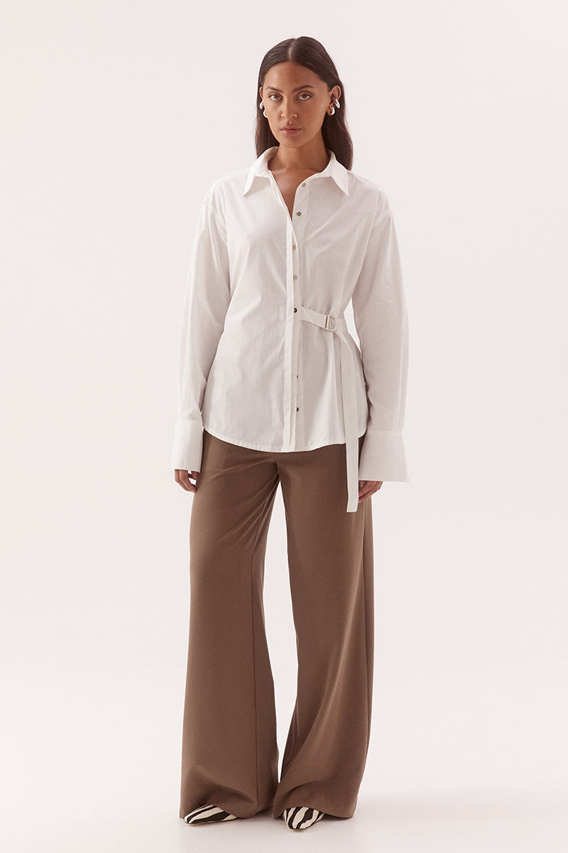 Women's relaxed fit cotton long sleeve shirt with dropped shoulders, silver metal buttons, adjustable belt detail, and side split shirtmaker hem.