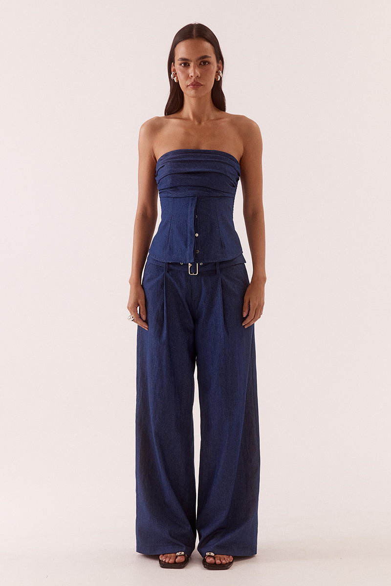 Model wearing wide leg cotton pants with front pleats, angled side pockets, back welt pockets, and a removable fabric belt with metal buckle.