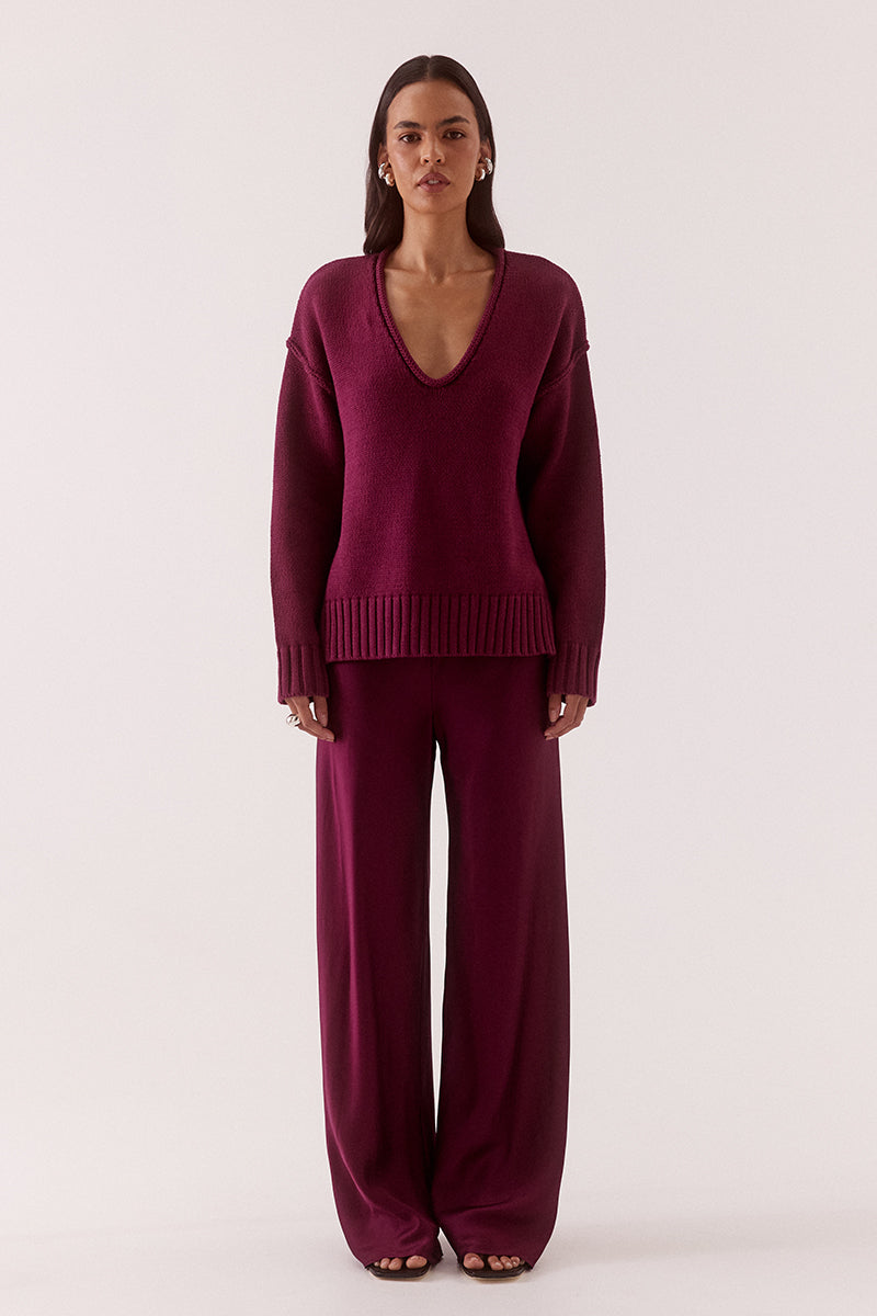 Women’s boxy knit sweater with plunging V-neckline, dropped shoulders, wide ribbed cuffs, and side split hem detail.