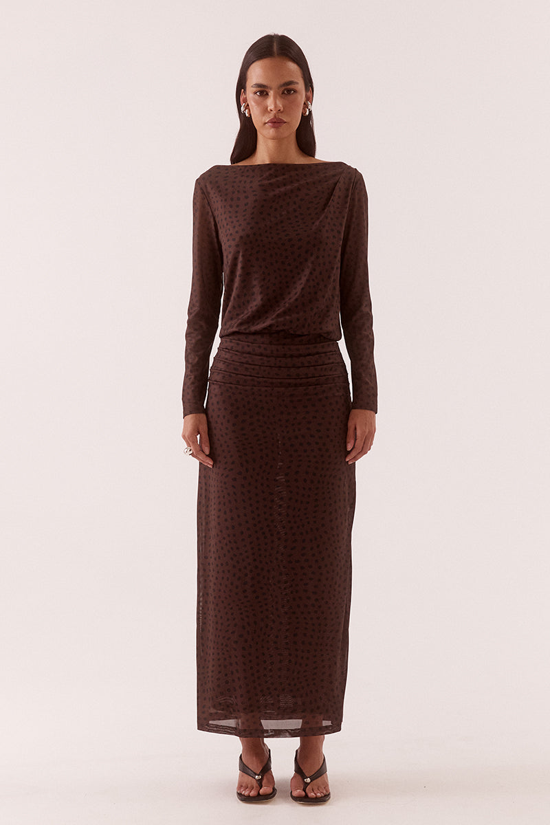Model wearing an exclusive print long sleeve maxi dress with boat neckline, tucked shoulder and hip detailing, elastic waist, and side split skirt.