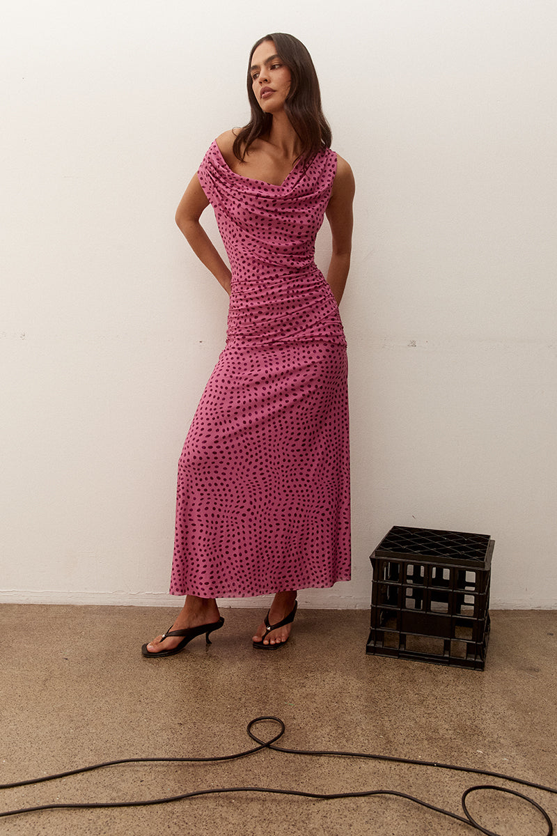 Model wearing an exclusive print sleeveless maxi dress with front and back cowl neckline, crossover gathered hip panels, and A-line skirt.