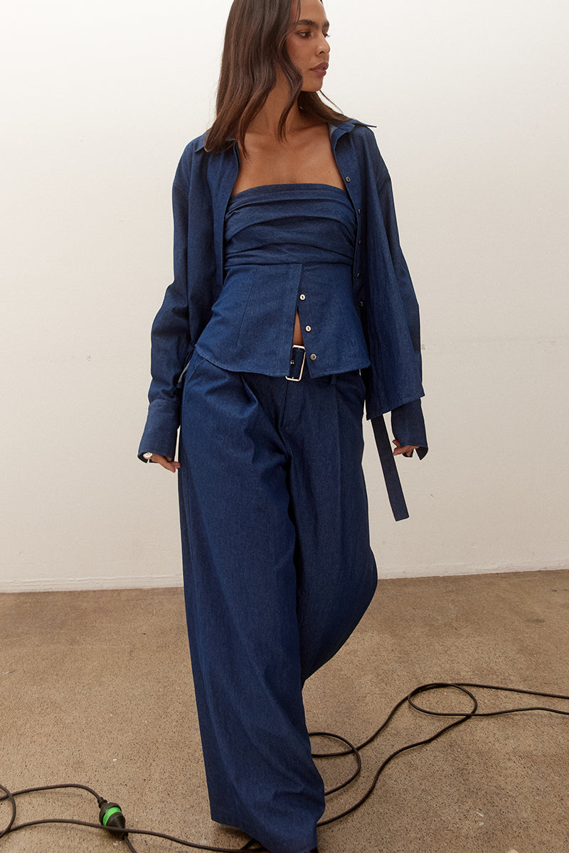 Model wearing a strapless cotton bodice with ruched upper detail, button front lower section, shirred sides and fitted structured silhouette.