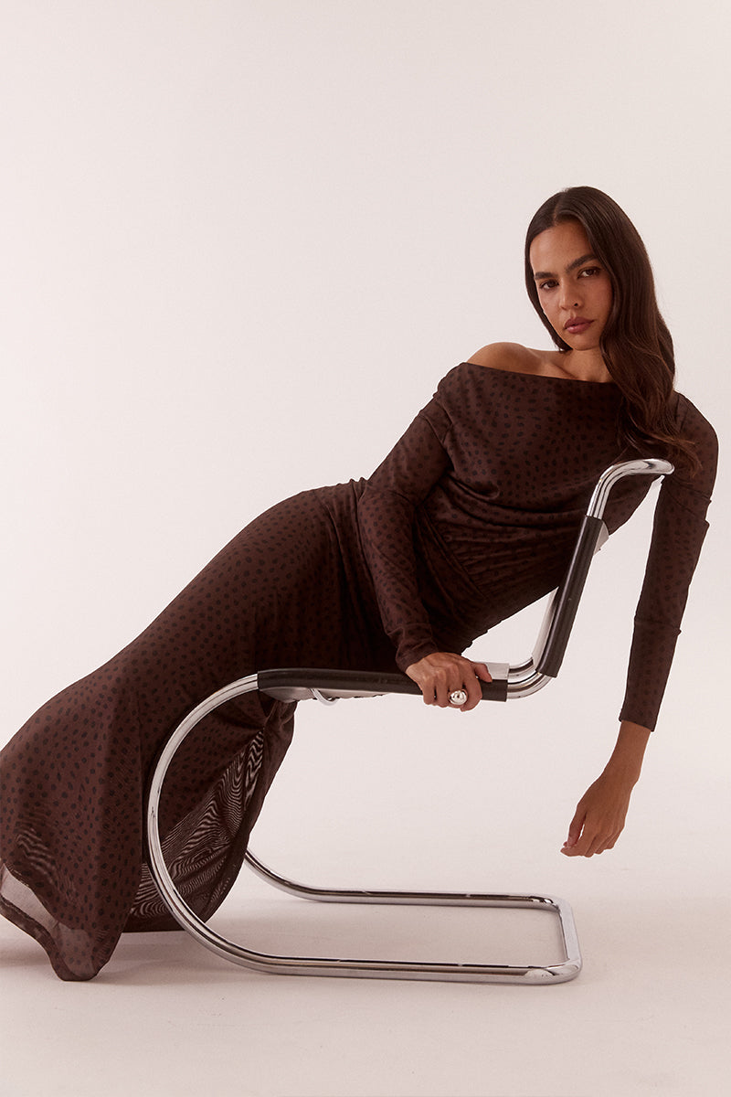 Model wearing an exclusive print long sleeve maxi dress with boat neckline, tucked shoulder and hip detailing, elastic waist, and side split skirt.