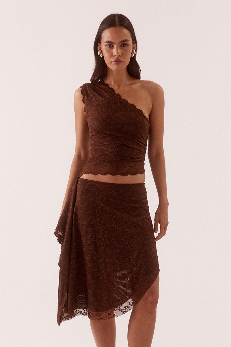 Model wearing a stretch lace one shoulder top with scalloped neckline, asymmetric hem and waist tuck detailing in a fitted silhouette.