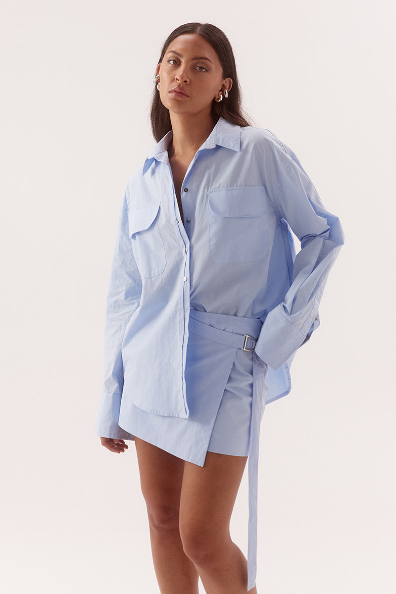 Women's cotton matching shirt and mini skirt set featuring relaxed fit shirt with chest pockets, and wrap-style A-line skirt with adjustable belt detail.