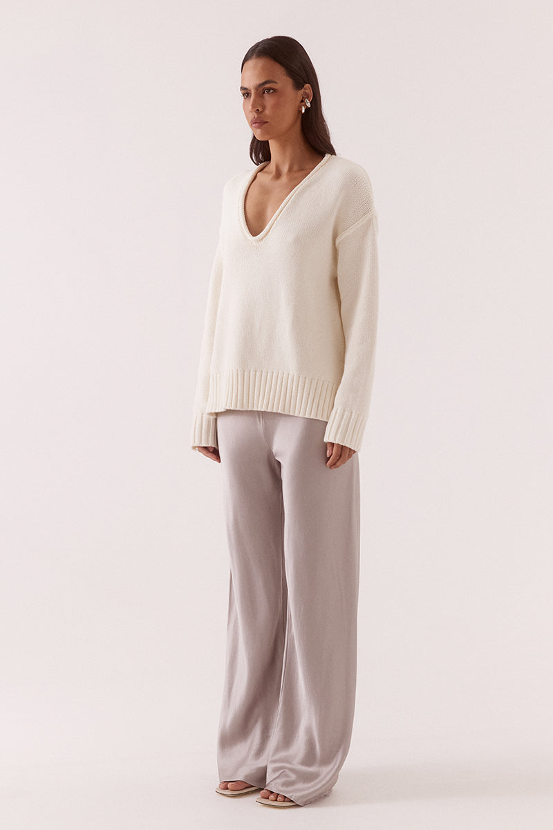 Women’s boxy knit sweater with plunging V-neckline, dropped shoulders, wide ribbed cuffs, and side split hem detail.