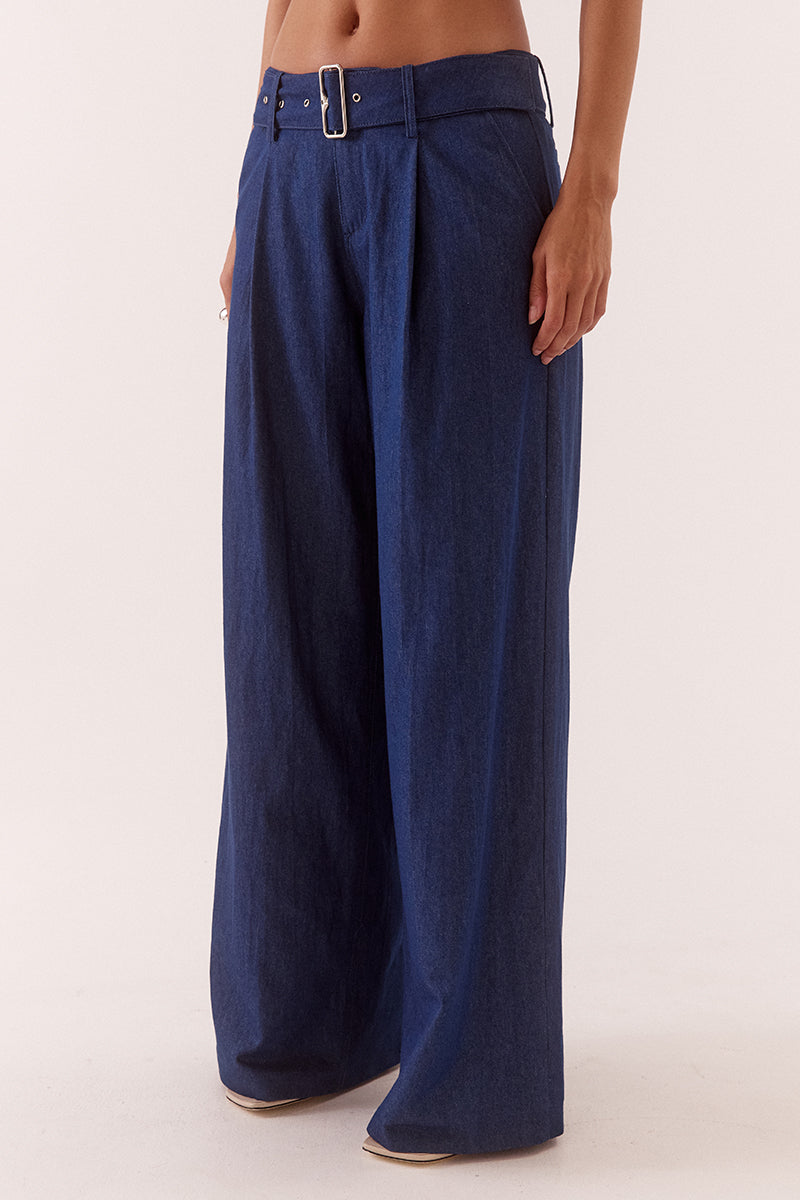 Model wearing wide leg cotton pants with front pleats, angled side pockets, back welt pockets, and a removable fabric belt with metal buckle.
