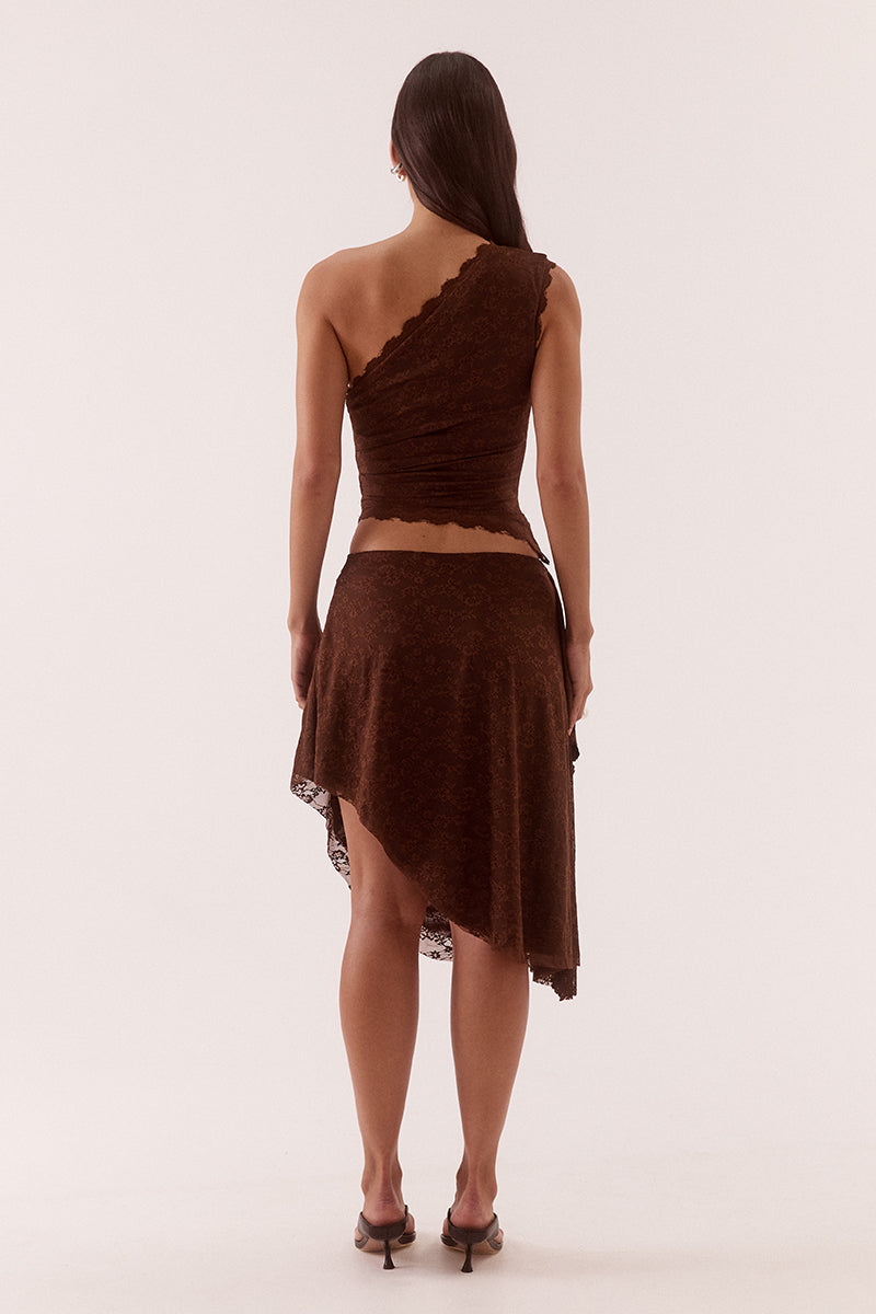 Model wearing a stretch lace one shoulder top with scalloped neckline, asymmetric hem and waist tuck detailing in a fitted silhouette.