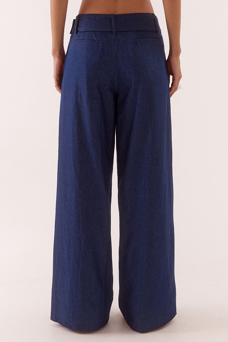 Model wearing wide leg cotton pants with front pleats, angled side pockets, back welt pockets, and a removable fabric belt with metal buckle.