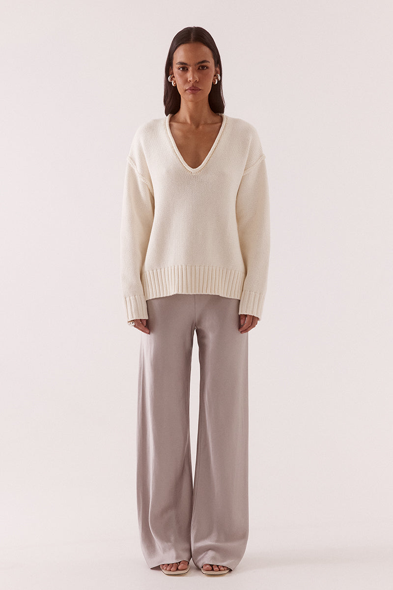 Women’s boxy knit sweater with plunging V-neckline, dropped shoulders, wide ribbed cuffs, and side split hem detail.