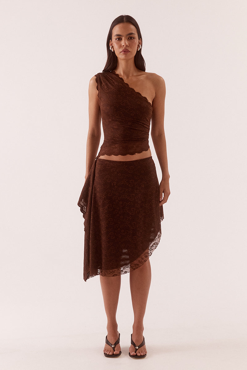 Model wearing a stretch lace one shoulder top with scalloped neckline, asymmetric hem and waist tuck detailing in a fitted silhouette.