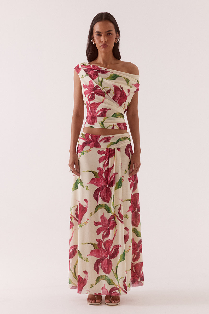 Model wearing an exclusive print stretch mesh maxi skirt with a fixed wrap silhouette, wide gathered waistband, hip seam gathering, and a flowing fully lined design.
