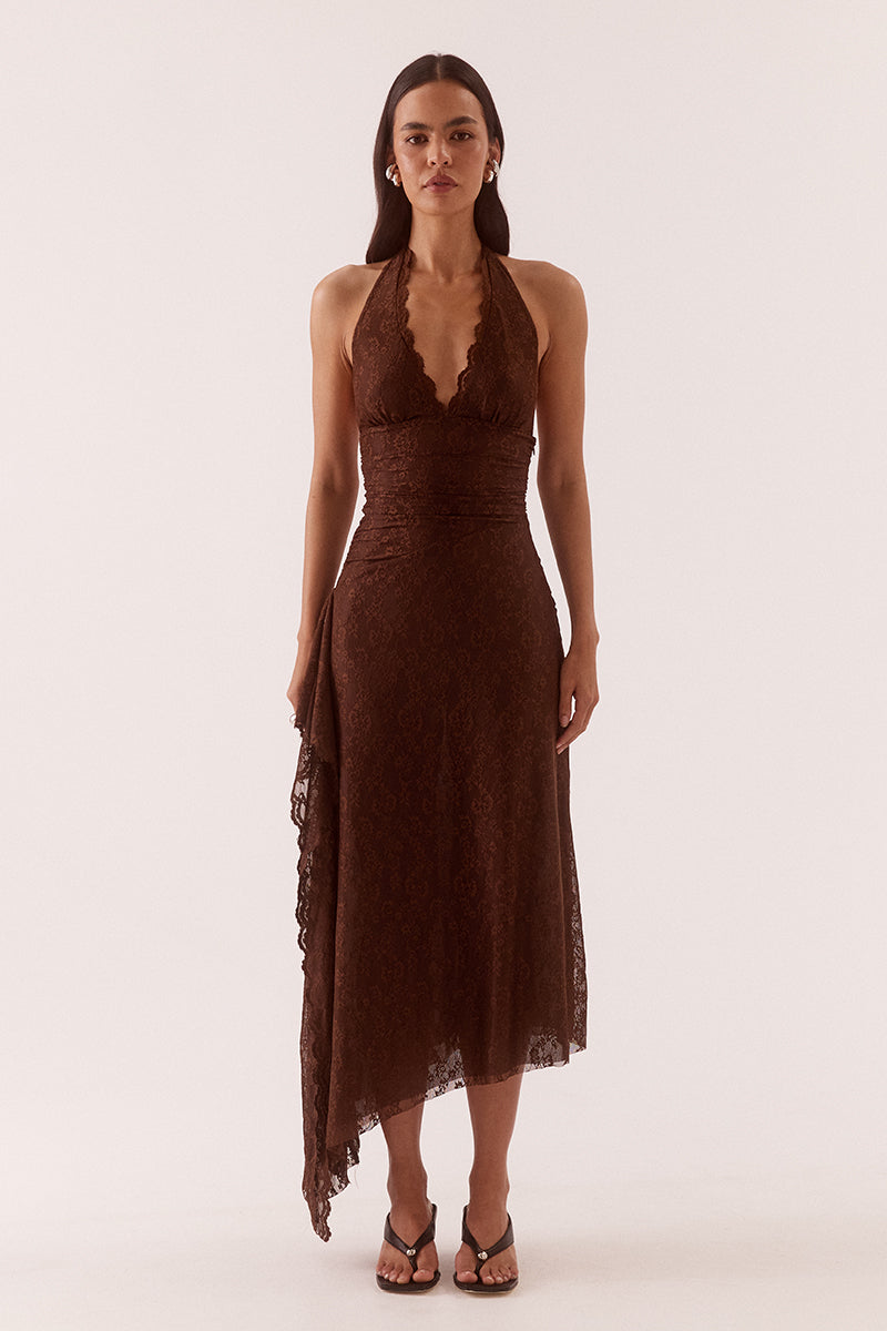 Model wearing a stretch lace halter midi dress with a plunging neckline, asymmetric hem, waterfall drape panel and scalloped edging.