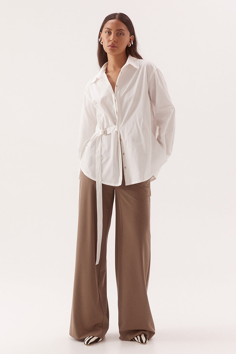 Women's relaxed fit cotton long sleeve shirt with dropped shoulders, silver metal buttons, adjustable belt detail, and side split shirtmaker hem.
