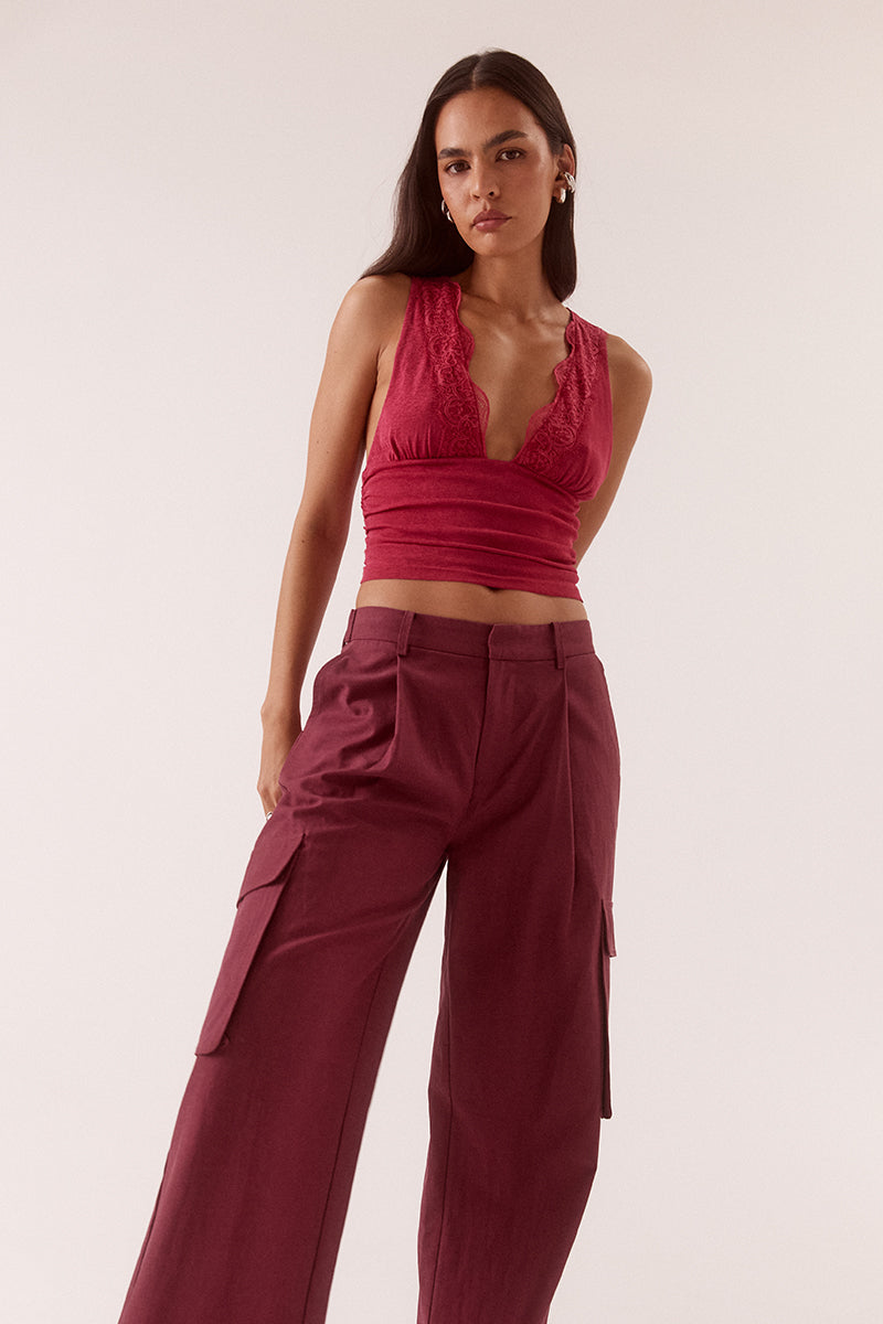 Textured stretch mesh sleeveless top with deep plunging neckline, lace trim, empire waist, and gathered front detail.