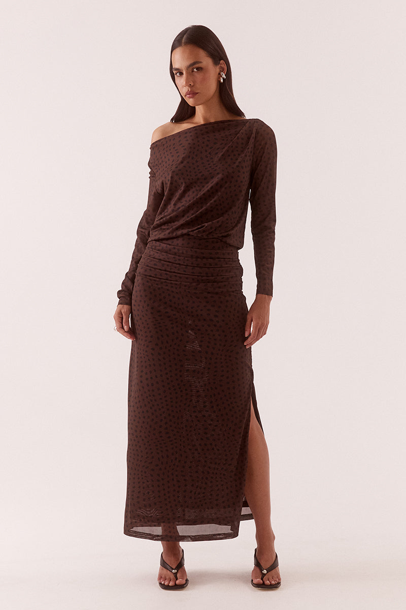 Model wearing an exclusive print long sleeve maxi dress with boat neckline, tucked shoulder and hip detailing, elastic waist, and side split skirt.