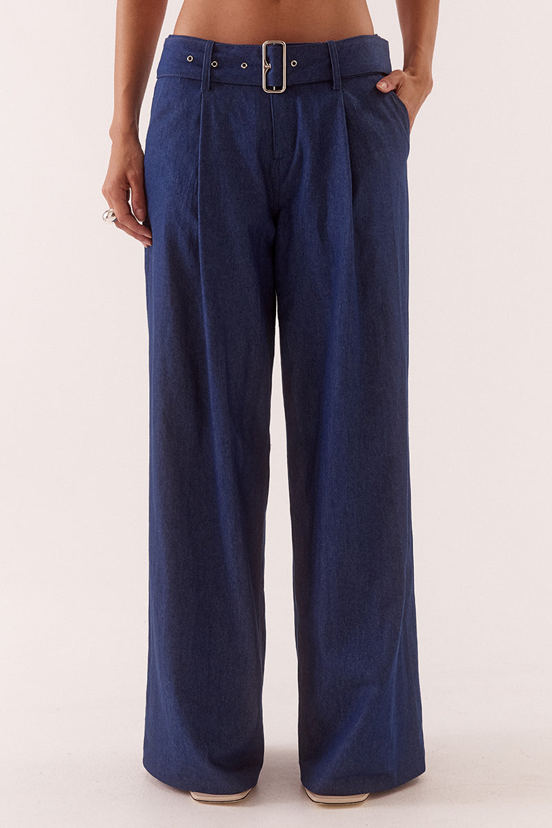 Model wearing wide leg cotton pants with front pleats, angled side pockets, back welt pockets, and a removable fabric belt with metal buckle.