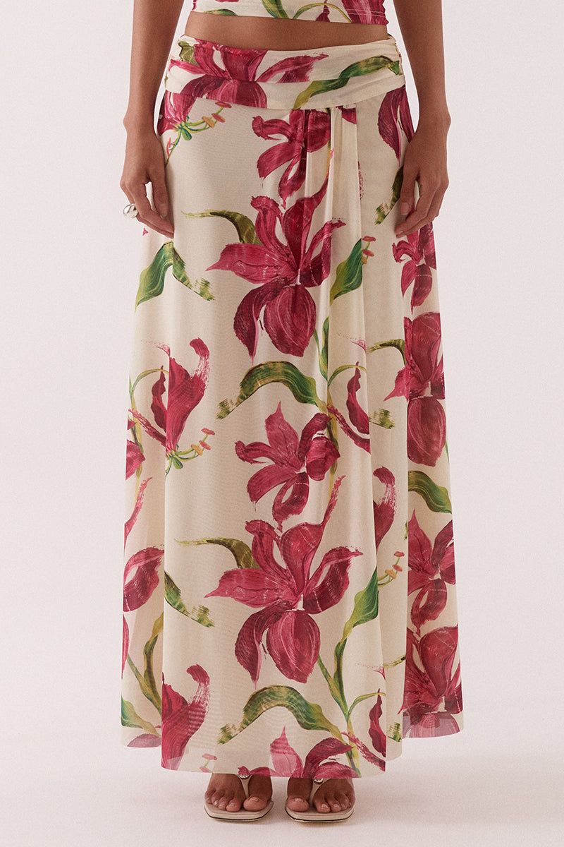 Model wearing an exclusive print stretch mesh maxi skirt with a fixed wrap silhouette, wide gathered waistband, hip seam gathering, and a flowing fully lined design.