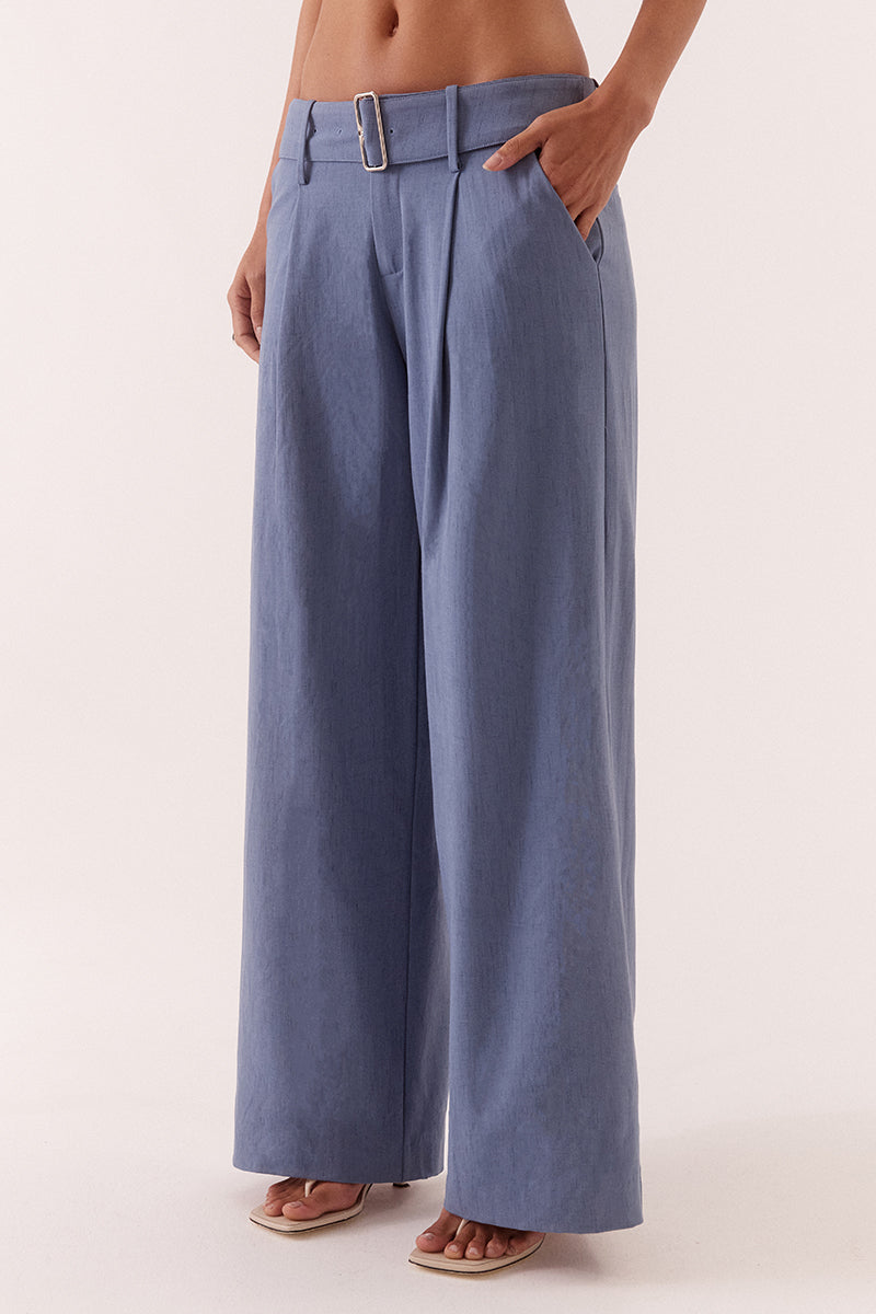 Women’s mid-rise wide leg pants in stretch rayon blend with front tucks, removable belt, angled pockets, and tailored fit with fly closure.