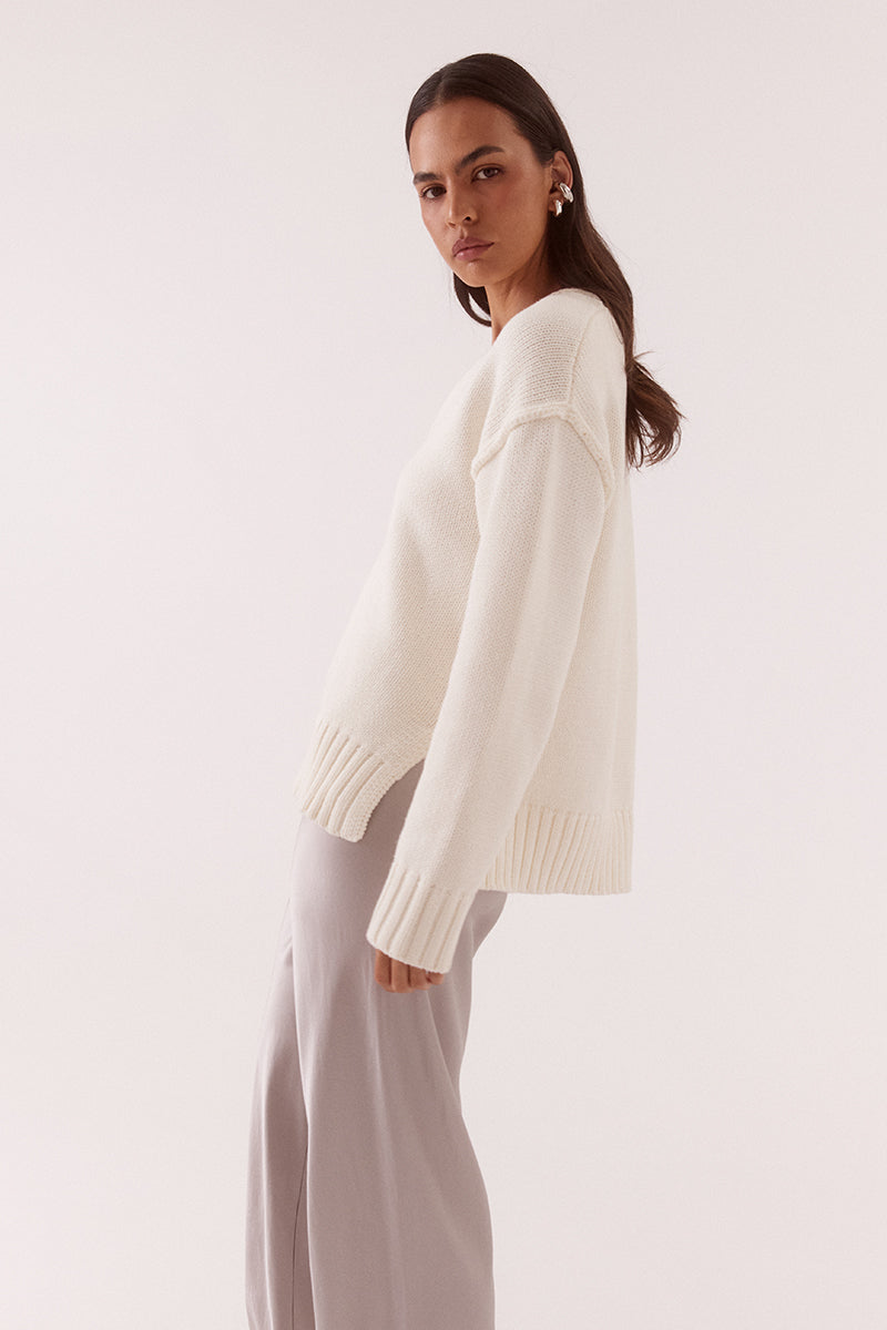 Women’s boxy knit sweater with plunging V-neckline, dropped shoulders, wide ribbed cuffs, and side split hem detail.