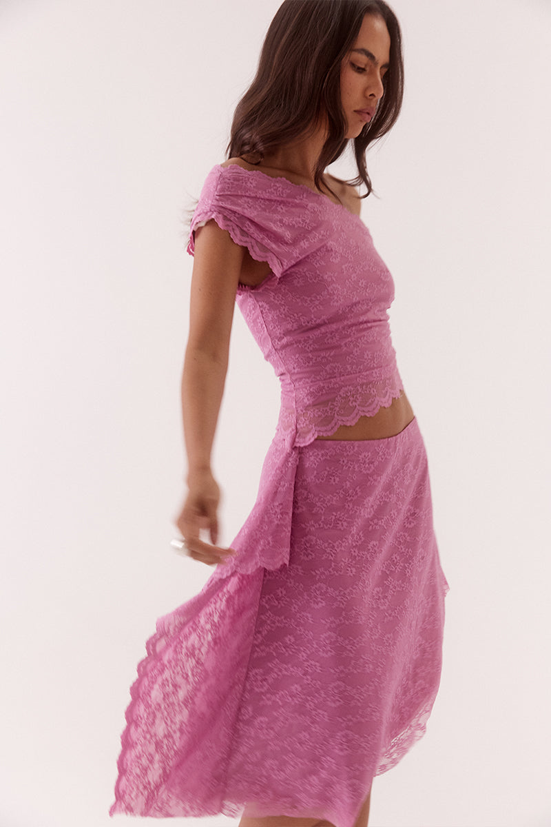 Model wearing a stretch lace one shoulder top with scalloped neckline, asymmetric hem and waist tuck detailing in a fitted silhouette.
