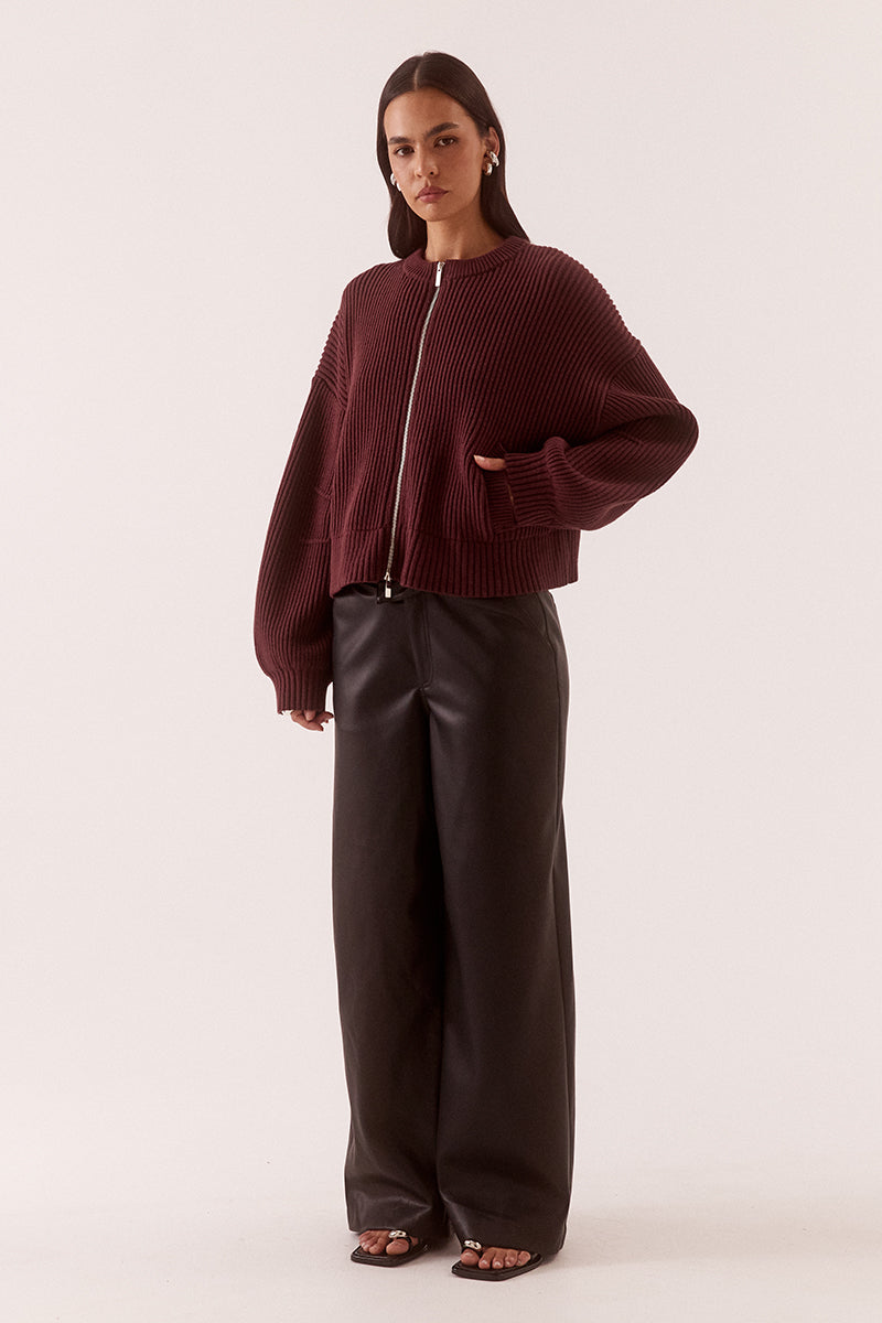 Model wearing a fully fashioned knit bomber cardigan with dropped shoulders, wide sleeves, ribbed trims, silver front zipper and welt pockets.
