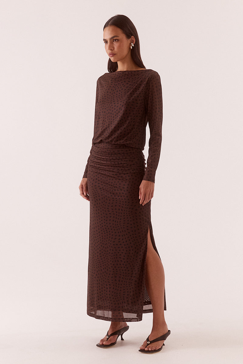 Model wearing an exclusive print long sleeve maxi dress with boat neckline, tucked shoulder and hip detailing, elastic waist, and side split skirt.