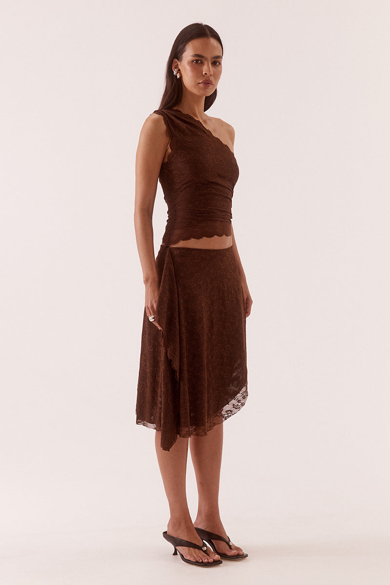 Model wearing a stretch lace one shoulder top with scalloped neckline, asymmetric hem and waist tuck detailing in a fitted silhouette.