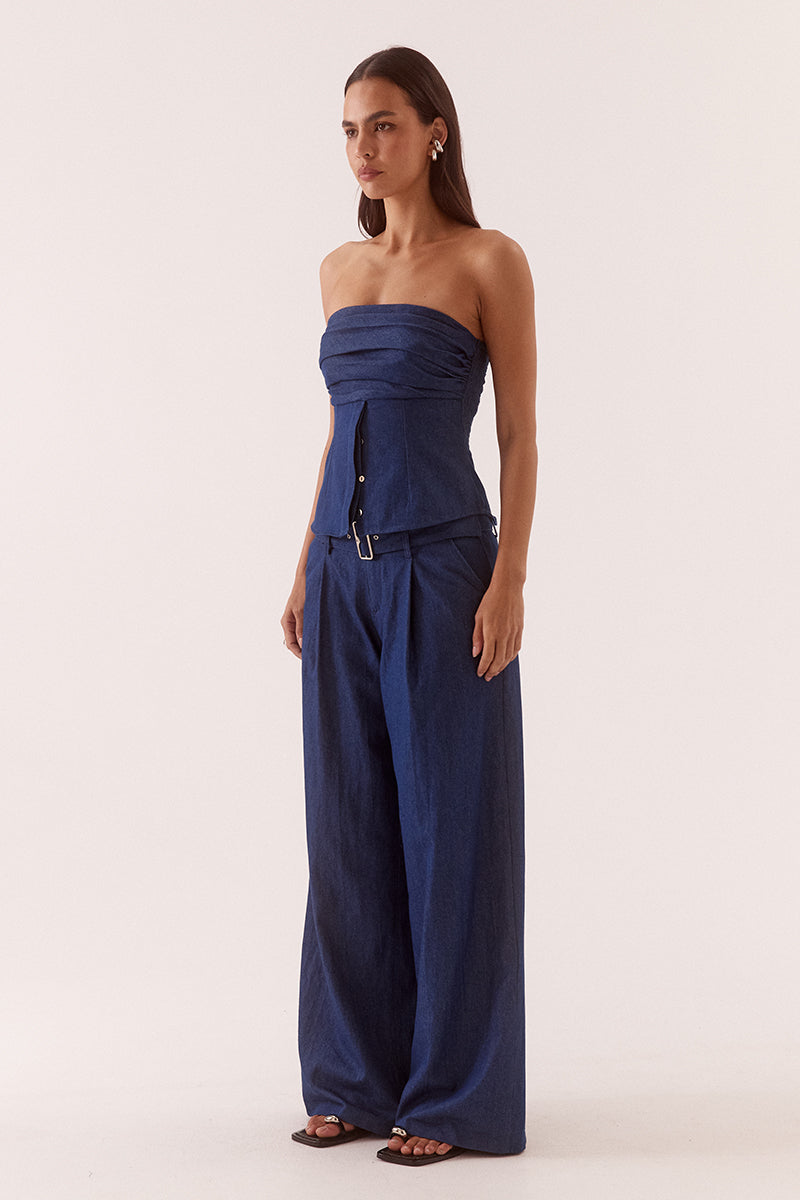 Model wearing a strapless cotton bodice with ruched upper detail, button front lower section, shirred sides and fitted structured silhouette.