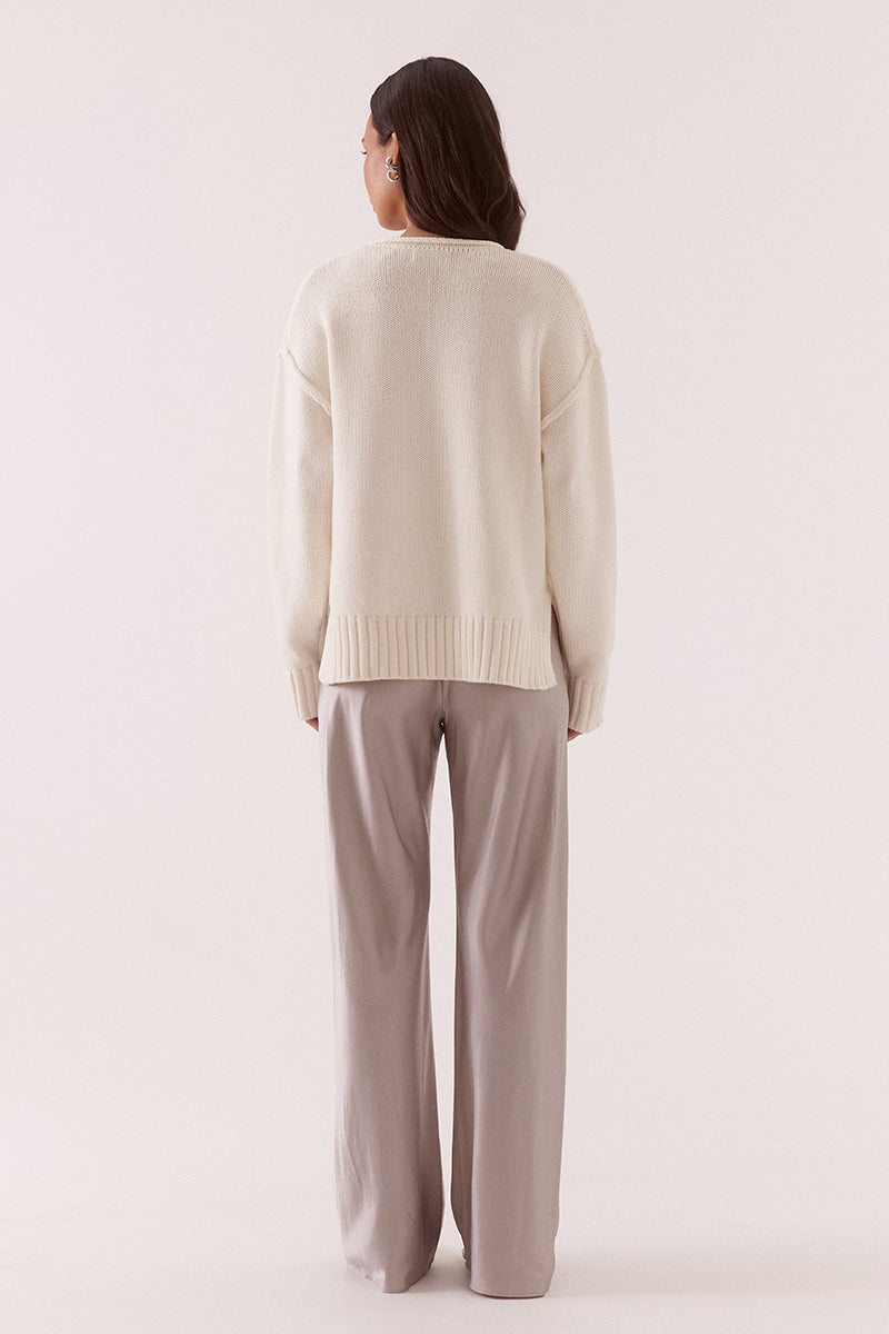 Women’s boxy knit sweater with plunging V-neckline, dropped shoulders, wide ribbed cuffs, and side split hem detail.