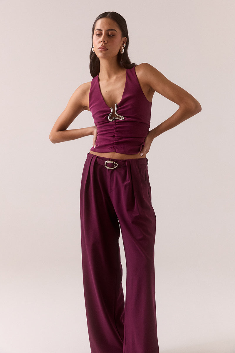 Fitted sleeveless V-neck top in stretchy fabric with silver chest hardware, gathered waist, racer back and pull-on design, fully lined, worn by model in size 8.