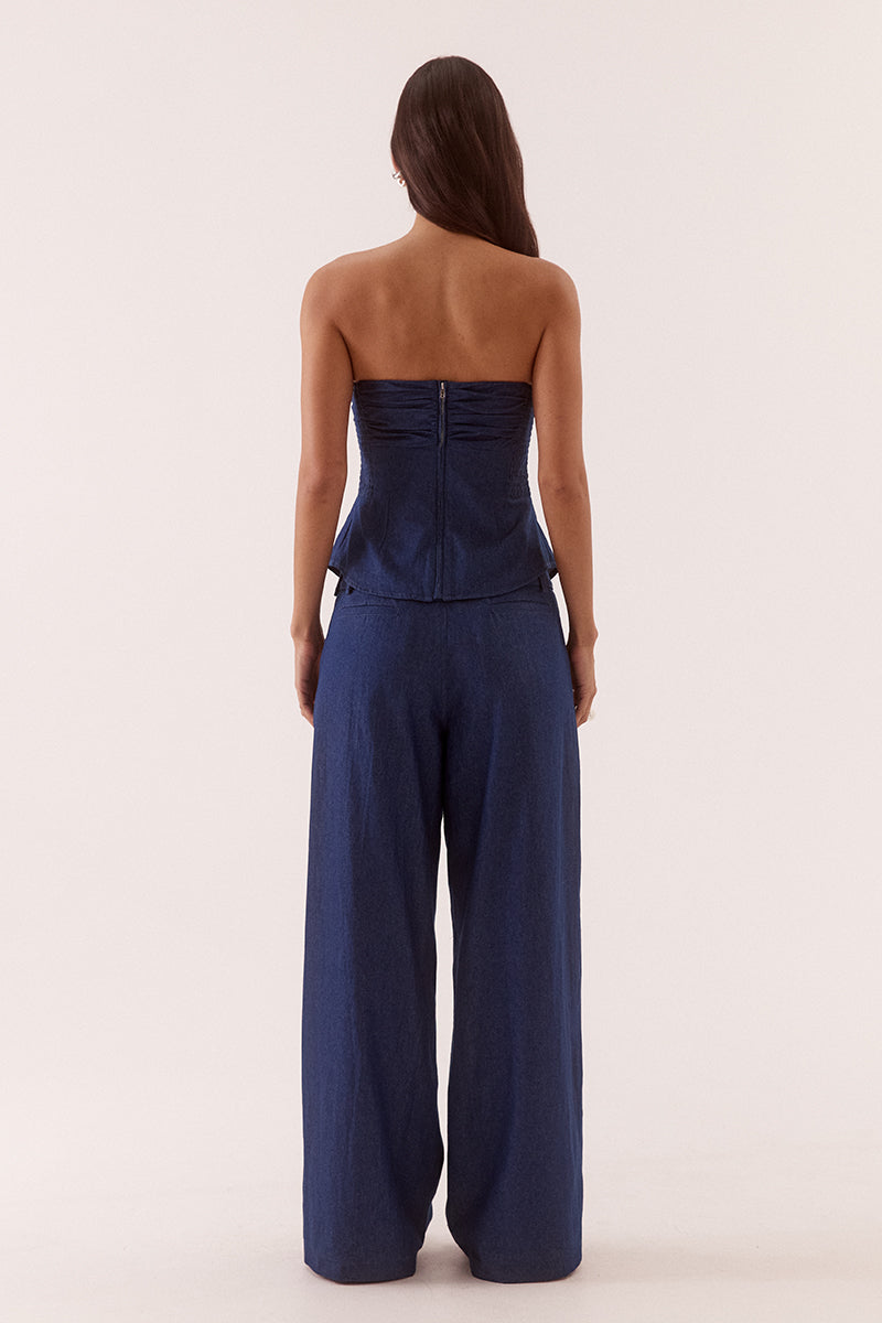 Model wearing a strapless cotton bodice with ruched upper detail, button front lower section, shirred sides and fitted structured silhouette.