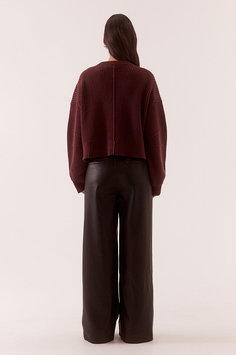 Model wearing a fully fashioned knit bomber cardigan with dropped shoulders, wide sleeves, ribbed trims, silver front zipper and welt pockets.