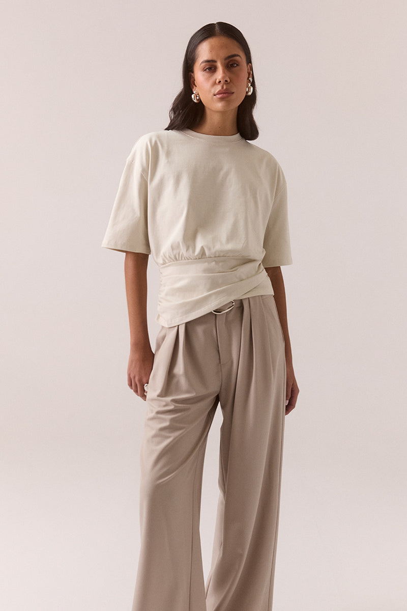 Relaxed fit 100% cotton T-shirt with crew neckline, dropped shoulders, asymmetrical drape hem layer and side invisible zipper, worn by model in size 8.