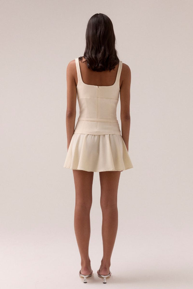 
                      
                        Woman wearing a white dress against a plain background
                      
                    