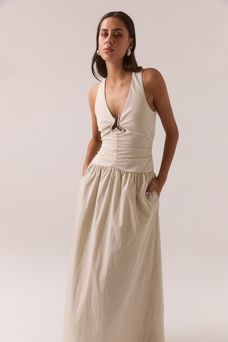 Sleeveless V-neck maxi dress in stretchy fabric with fitted bodice, full skirt, silver chest hardware, elasticated dropped waist and racer back, worn by model in size 8.