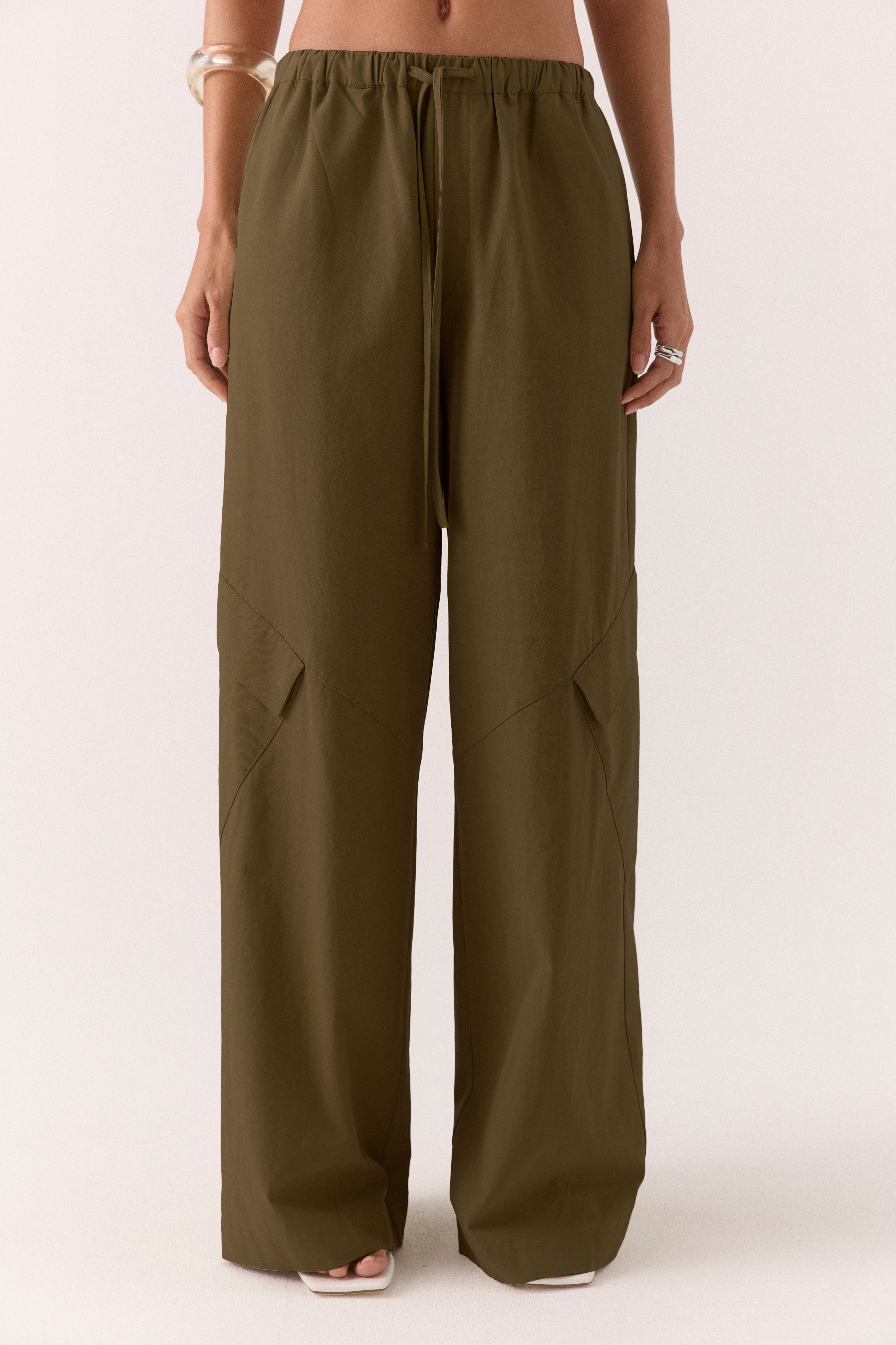 Model wearing lyocell blend straight leg cargo pants with elastic drawstring waist, angled front pockets and side cargo pocket.